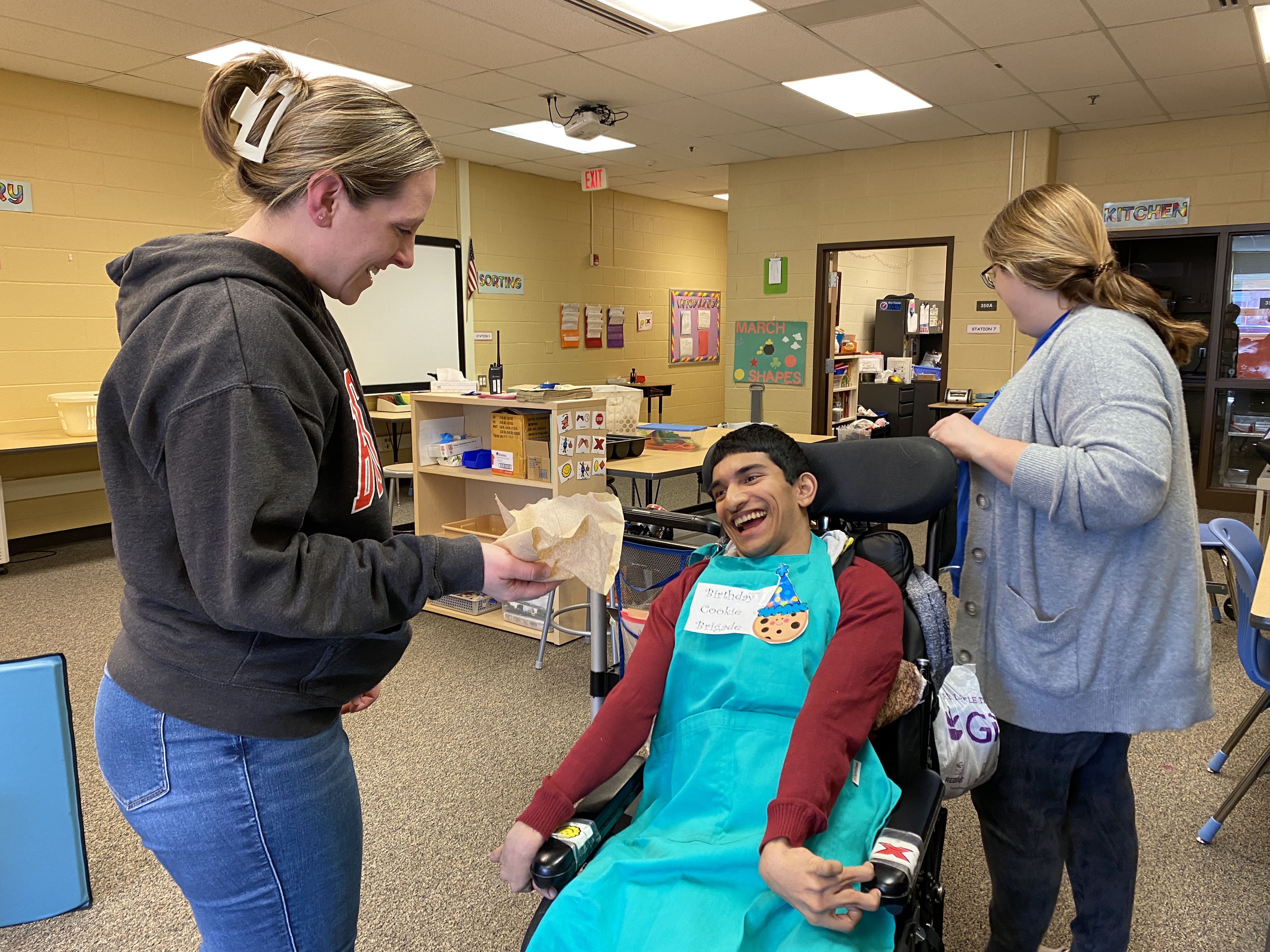 a student in a wheelchair delivers a cookie to a teacher