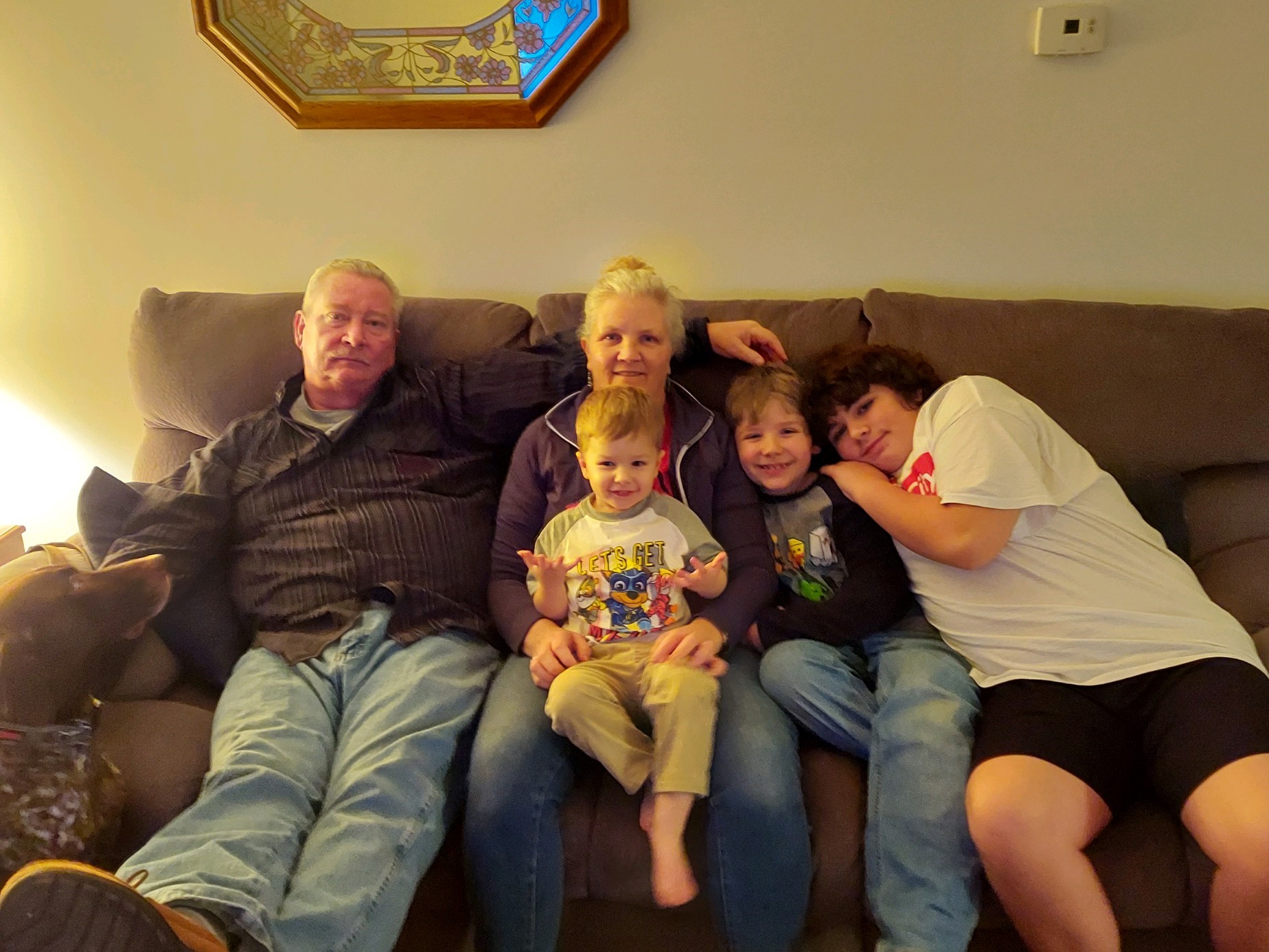 Patricia with her husband and 3 grandsons sitting on a couch